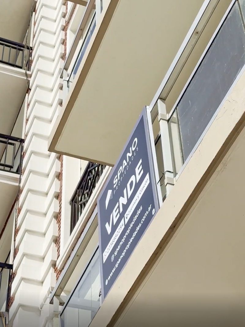 Cartel de Spano Propiedades VENDE en el balcón de un edificio